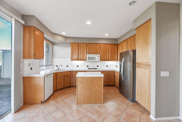kitchen with recessed lighting, light countertops, white appliances, a center island, and tasteful backsplash