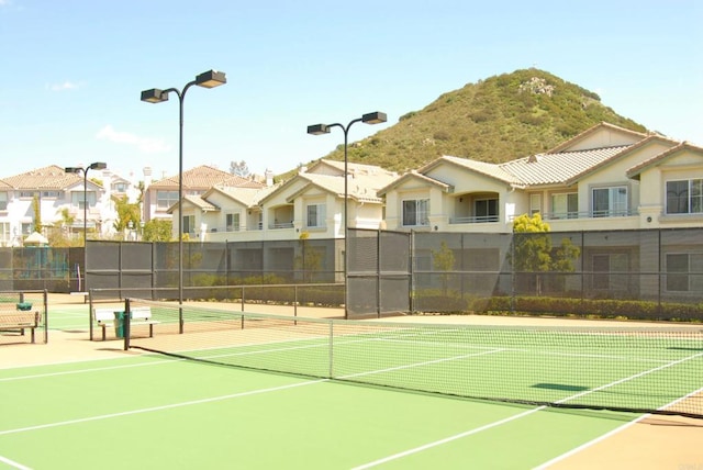 view of sport court with fence, a mountain view, and a residential view