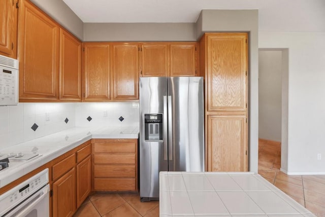 kitchen featuring white appliances, tile countertops, light tile patterned floors, and tasteful backsplash