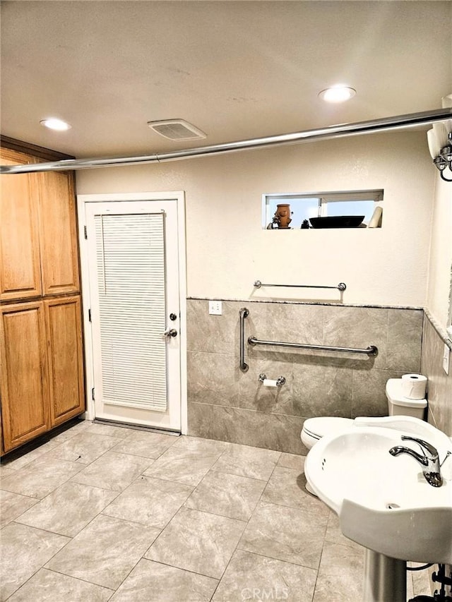 15433 Idaho Ln, Apple Valley, CA 92307 - bathroom with toilet, a sink, a wainscoted wall, and tile walls