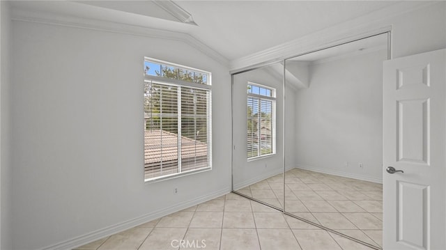 spare room with ornamental molding, baseboards, light tile patterned floors, and lofted ceiling