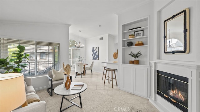 living room with a glass covered fireplace, built in features, an inviting chandelier, ornamental molding, and light tile patterned floors