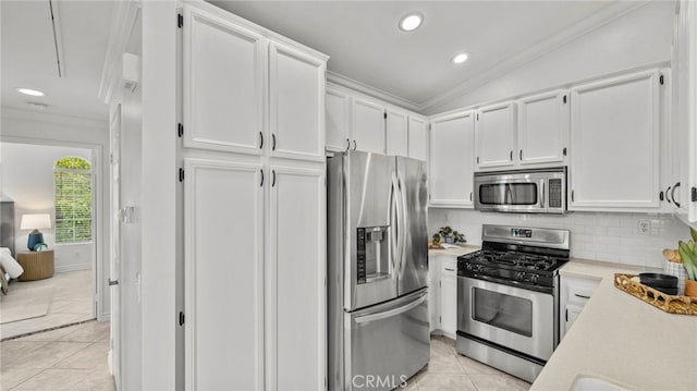 kitchen with light tile patterned floors, ornamental molding, white cabinetry, light countertops, and stainless steel appliances