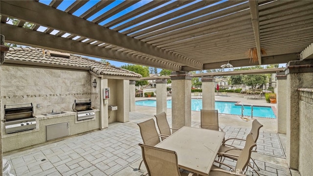 view of patio with a pergola, a community pool, a grill, and an outdoor kitchen