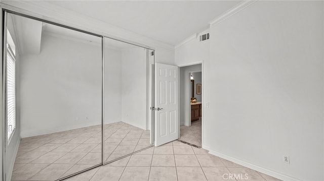 unfurnished bedroom with ornamental molding, multiple windows, a closet, and light tile patterned flooring