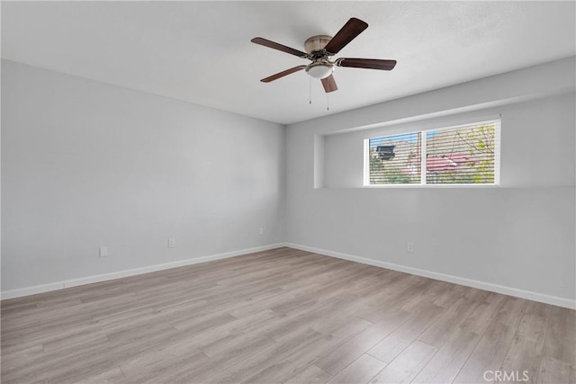 empty room with baseboards, light wood-style floors, and a ceiling fan