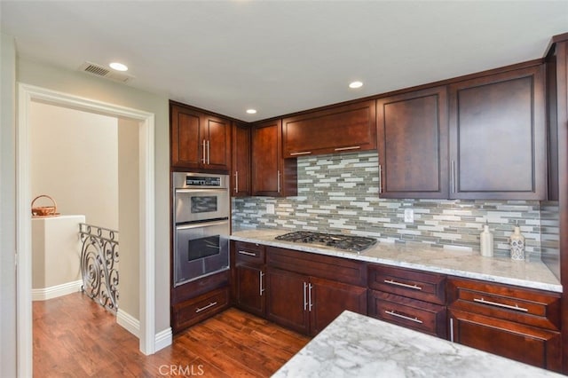 kitchen featuring dark wood-style floors, light stone countertops, visible vents, and appliances with stainless steel finishes