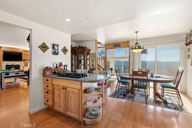 27721 Caribou Dr, Lake Arrowhead, CA 92352 - kitchen featuring black gas stovetop, open shelves, light wood-style flooring, dark countertops, and hanging light fixtures