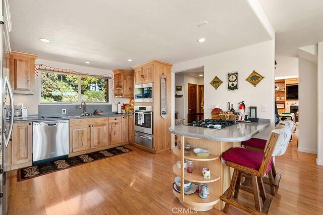 27721 Caribou Dr, Lake Arrowhead, CA 92352 - kitchen featuring appliances with stainless steel finishes, a warming drawer, open shelves, a breakfast bar area, and a peninsula