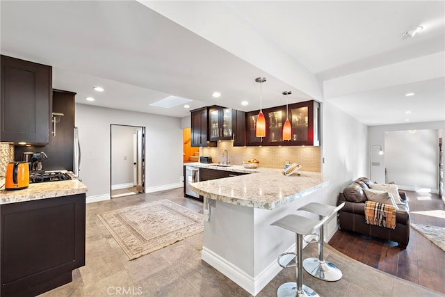 kitchen with a kitchen bar, tasteful backsplash, glass insert cabinets, and baseboards