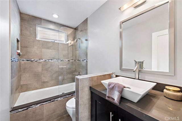 bathroom featuring recessed lighting, toilet, vanity, and tiled shower / bath