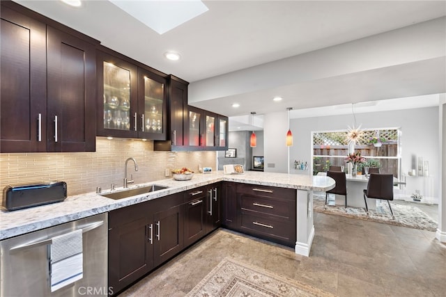 kitchen with dark brown cabinets, a peninsula, a sink, and light stone counters