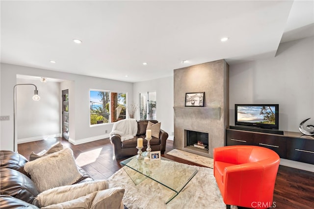 living room with baseboards, a premium fireplace, wood finished floors, and recessed lighting