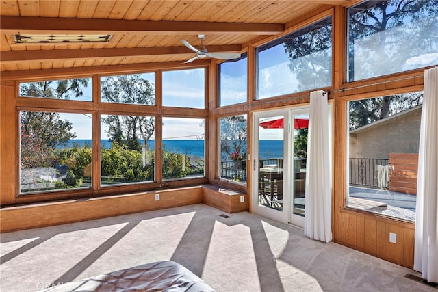 unfurnished sunroom featuring carpet floors, a water view, wood ceiling, and plenty of natural light