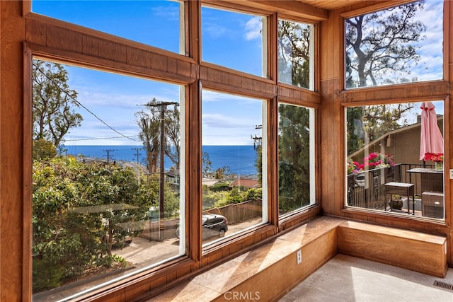 unfurnished sunroom with visible vents, carpet floors, a wealth of natural light, and a high ceiling