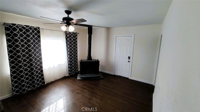 Palmdale, CA 93591 - empty room featuring a wood stove, ceiling fan, and dark wood finished floors