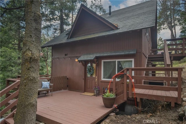 exterior space featuring a shingled roof, stairs, and a wooden deck