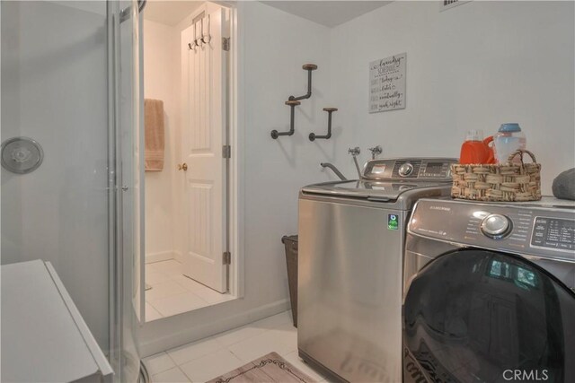 clothes washing area with washing machine and dryer, laundry area, and light tile patterned floors