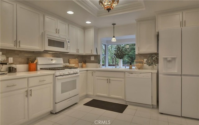 kitchen featuring a sink, light countertops, a raised ceiling, and white appliances