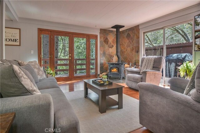 living room featuring a healthy amount of sunlight, wood finished floors, a wood stove, and wood ceiling