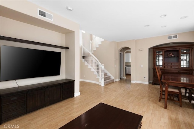 6050 Paseo Carreta, Carlsbad, CA 92009 - living room featuring visible vents, arched walkways, light wood finished floors, and stairway