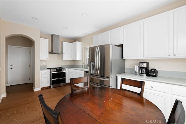 6050 Paseo Carreta, Carlsbad, CA 92009 - kitchen featuring white cabinetry, stainless steel appliances, arched walkways, dark wood-style flooring, and wall chimney exhaust hood