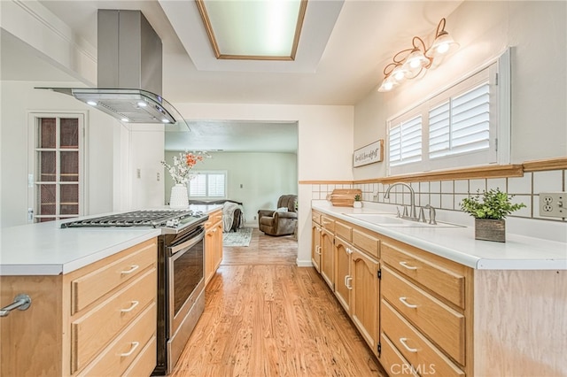 8029 Fruitland Ave, Winton, CA 95388 - kitchen featuring stainless steel gas stove, light wood-style flooring, a sink, light countertops, and island range hood
