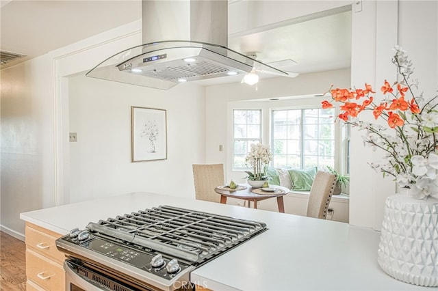 8029 Fruitland Ave, Winton, CA 95388 - kitchen featuring light wood-style floors, stainless steel range with gas cooktop, visible vents, light countertops, and island range hood