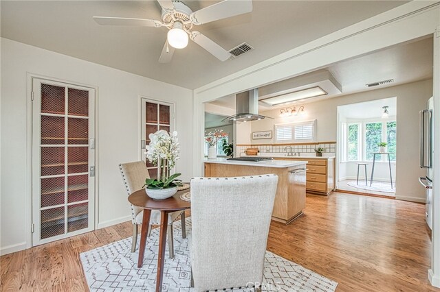 8029 Fruitland Ave, Winton, CA 95388 - kitchen featuring light wood finished floors, visible vents, light countertops, and island exhaust hood