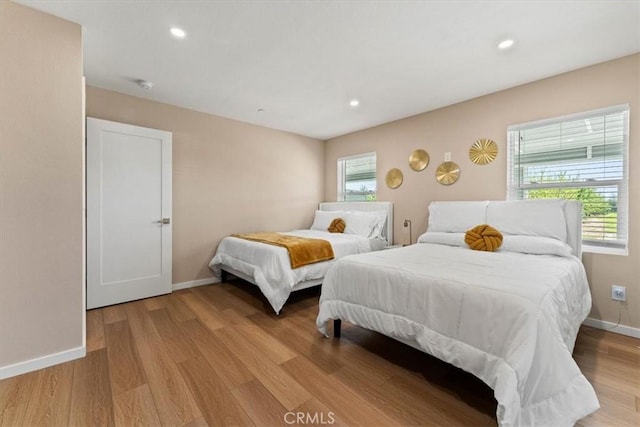 bedroom featuring baseboards, multiple windows, light wood finished floors, and recessed lighting