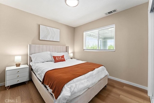 bedroom featuring wood finished floors, baseboards, and visible vents