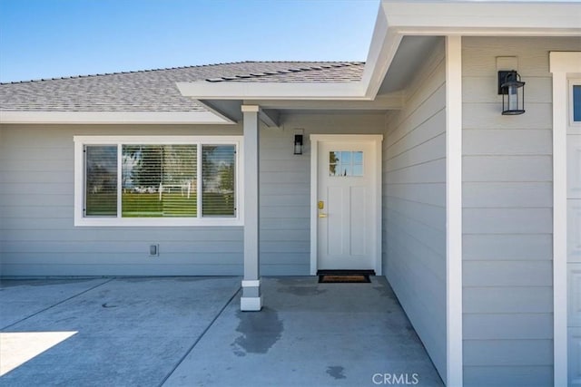 doorway to property with roof with shingles