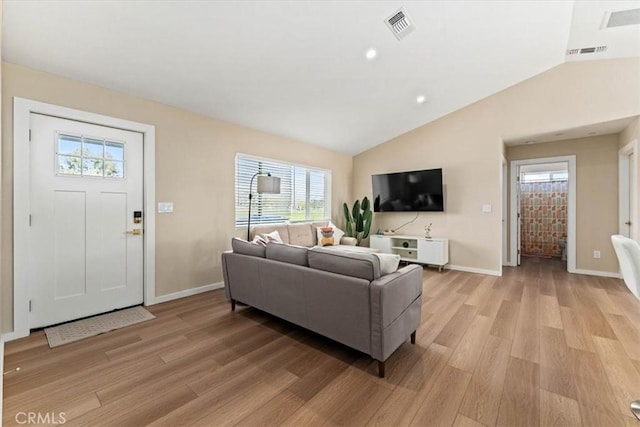 living room featuring baseboards, light wood-style floors, lofted ceiling, and visible vents