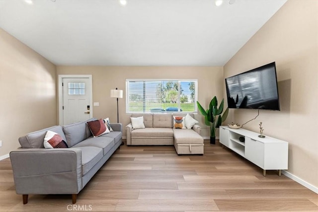 living room with baseboards, vaulted ceiling, and light wood-style flooring