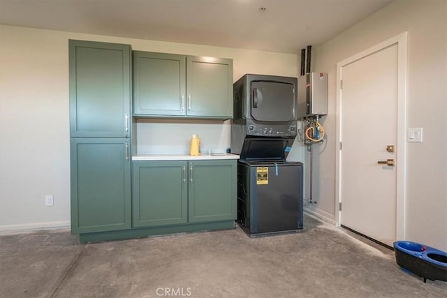 kitchen with stacked washer and dryer, light countertops, green cabinetry, and concrete flooring