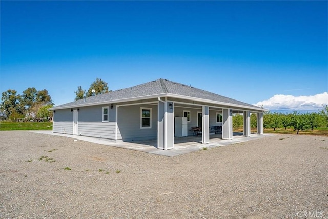 rear view of property with a shingled roof and a patio area