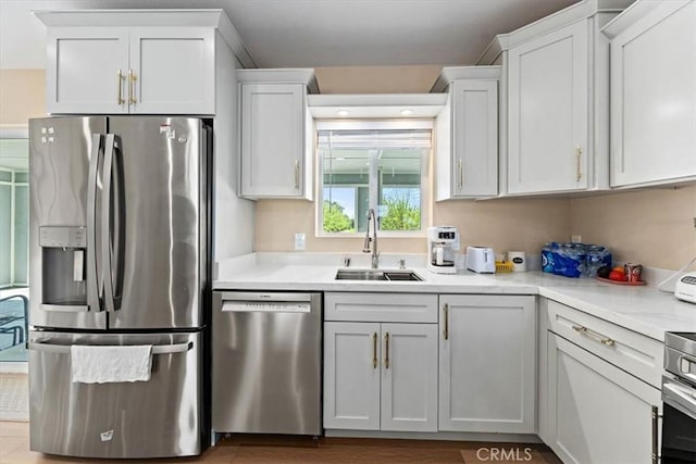 kitchen with white cabinets, a sink, light countertops, and appliances with stainless steel finishes