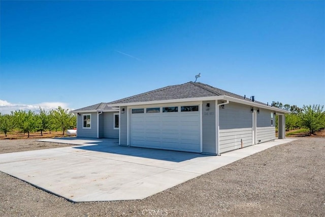 ranch-style house with concrete driveway, roof with shingles, and an attached garage