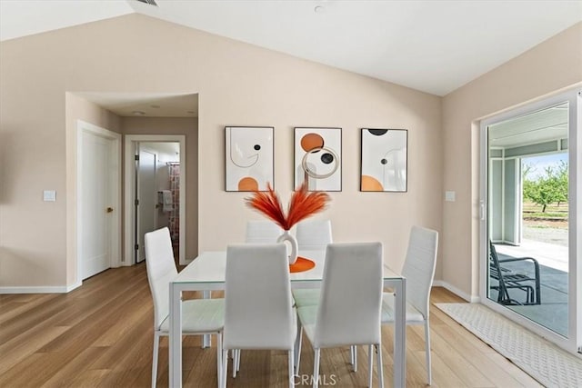 dining room featuring light wood-style flooring, baseboards, and lofted ceiling