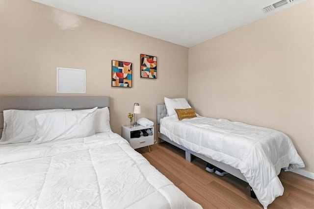 bedroom featuring wood finished floors, baseboards, and visible vents