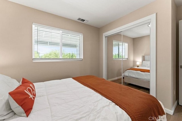 bedroom featuring a closet, baseboards, multiple windows, and visible vents