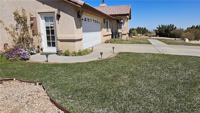 view of side of property with a tiled roof, a yard, a garage, stucco siding, and driveway