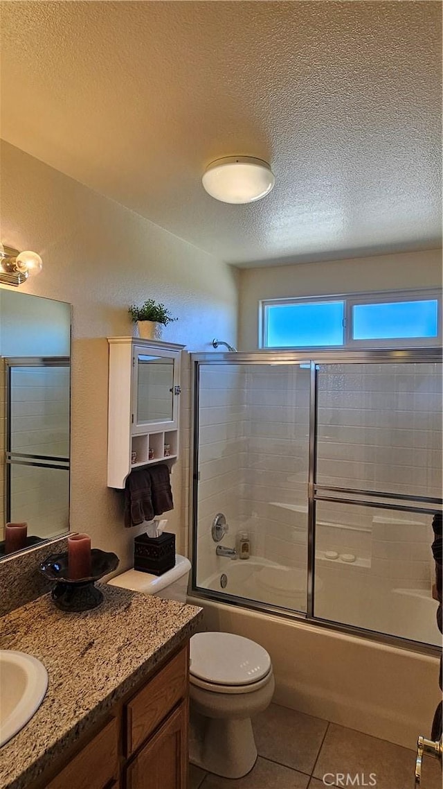 bathroom featuring tile patterned flooring, a textured ceiling, vanity, and a healthy amount of sunlight