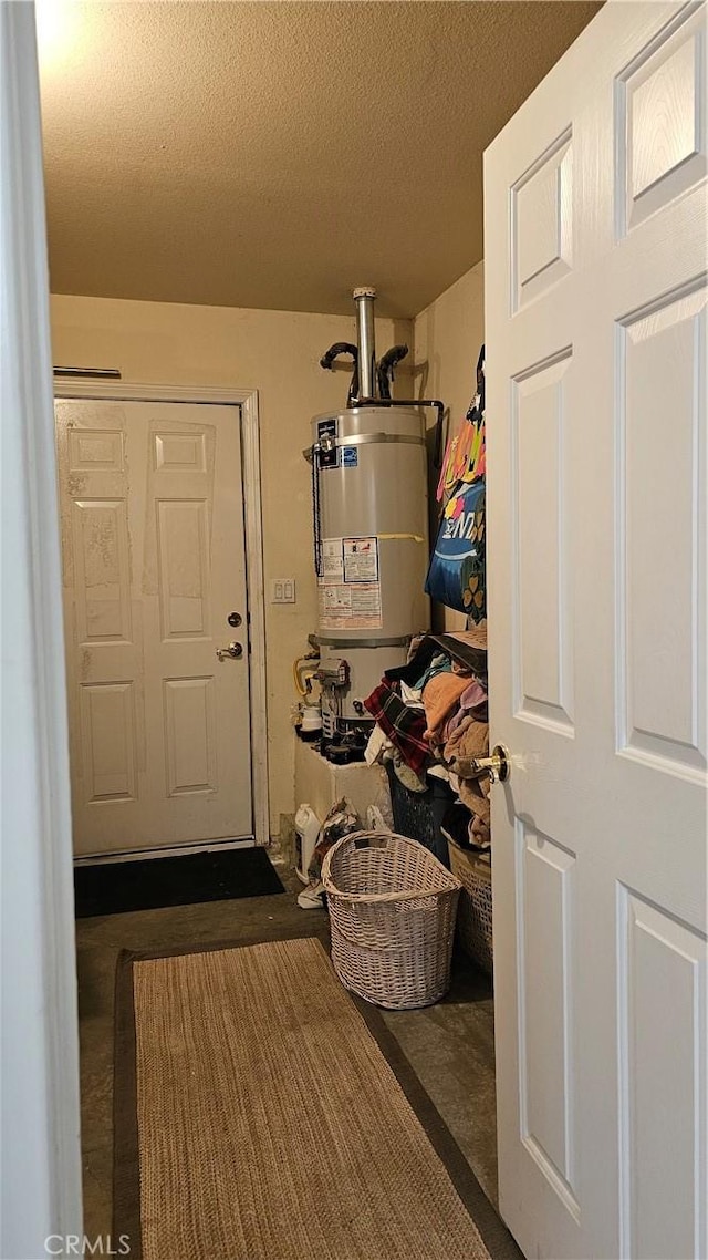 interior space with water heater, a textured ceiling, and concrete flooring