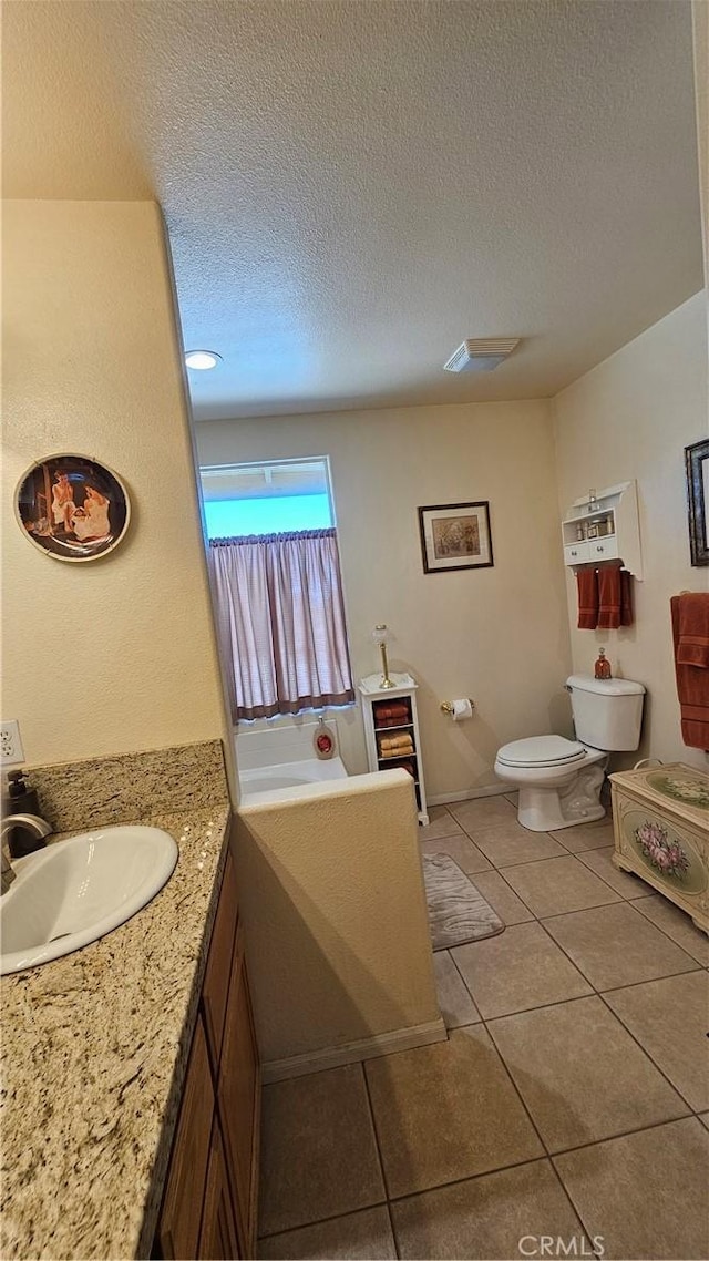 bathroom featuring tile patterned floors, vanity, a textured ceiling, and toilet