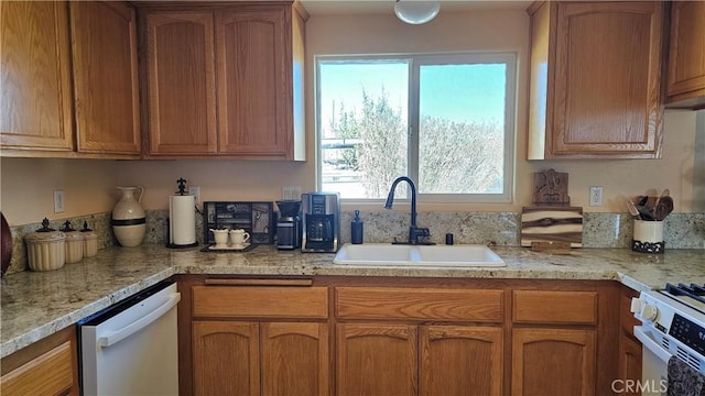 kitchen featuring brown cabinets, a sink, white appliances, and plenty of natural light