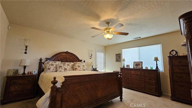 bedroom with visible vents, light colored carpet, a textured ceiling, and ceiling fan