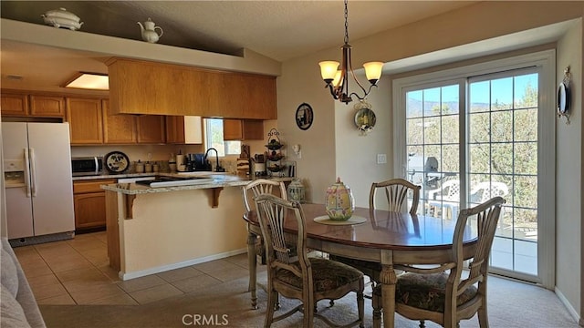 dining room featuring a chandelier, light tile patterned floors, and lofted ceiling