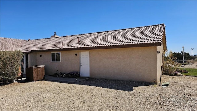rear view of house featuring a tiled roof and stucco siding