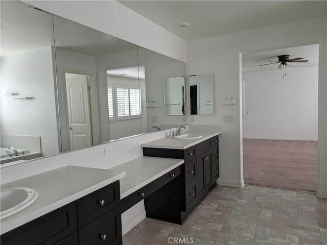 bathroom featuring baseboards, stone finish flooring, vanity, and a ceiling fan